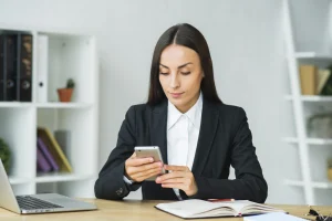 attractive-young-businesswoman-checking-cellphone-workplace