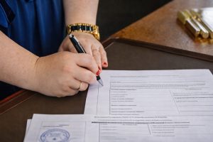 Person signing a document on a desk.